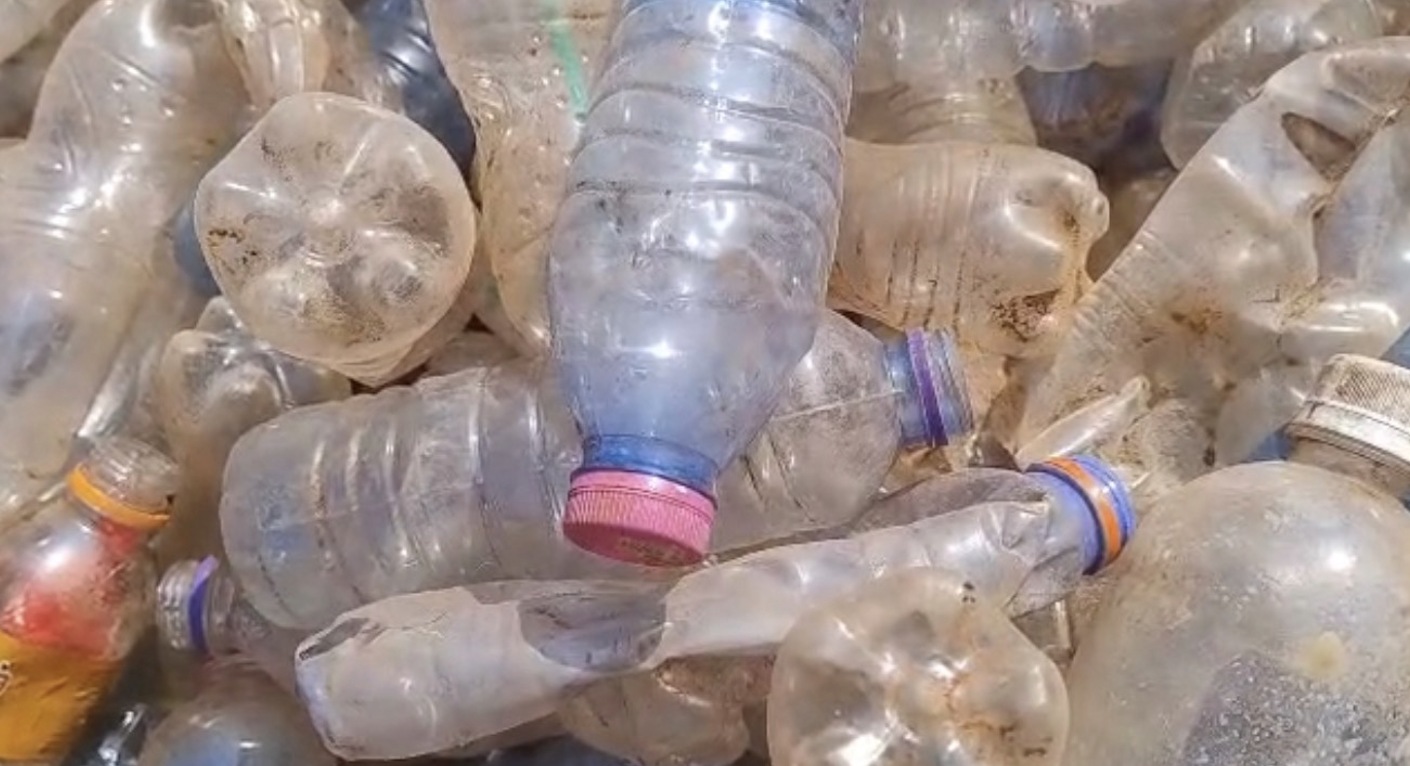 A pile of loose, dirty plastic bottles